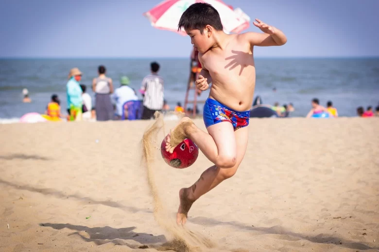 Criança pequena brincando em uma das melhores praias para crianças no Brasil, com mar calmo e cristalino