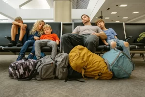 Pai consolando filho em um aeroporto, mostrando a verdade sobre viajar com crianças.
